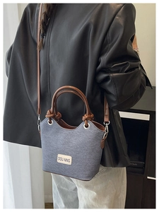 Sac seau en denim bleu avec anse en cuir marron porté par un mannequin pour le style