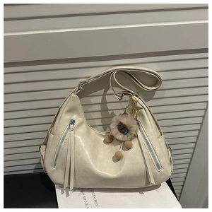 Detailed view of off-white tote bag with silver zippers and a cute plush lion charm