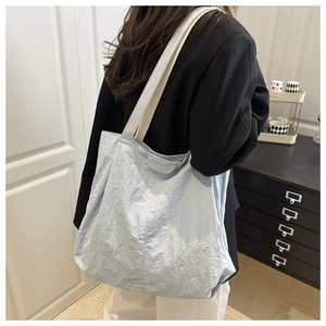 Close-up of a light blue pleated nylon tote bag with fashion tag and gray shoulder strap