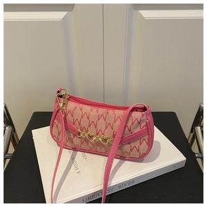 Dettaglio del tessuto jacquard rosa con motivi M e accessorio a catena con cuore dorato