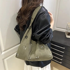 Minimalist green knit tote bag with flower laser-cut design shown on a model shoulder