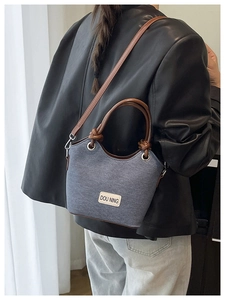 Détails du sac seau gris avec poignées en cuir marron et étiquette de marque