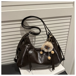 Detail of dark brown leather tote with double zip fringe and cute plush keychain