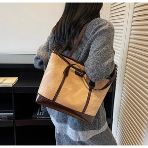 Model view of large khaki vintage tote bag with dark brown leather straps and metal logo