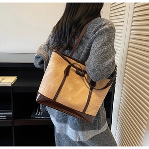 Detail of canvas tote bag showing beige fabric, brown leather trim, and dual shoulder straps