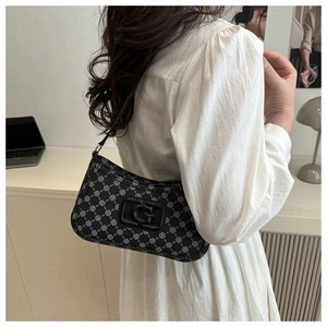 Detail of vintage French black baguette bag with white pattern and G logo on model