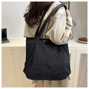 Detail of black canvas tote bag with wrinkled texture and fashion embossed leather patch