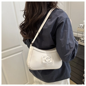 Detailed view of white minimalist shoulder bag with G logo on a model