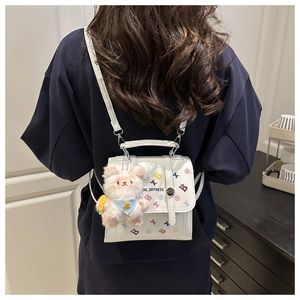 Détail du sac à dos blanc brillant avec logo coloré et breloque lapin en peluche rose
