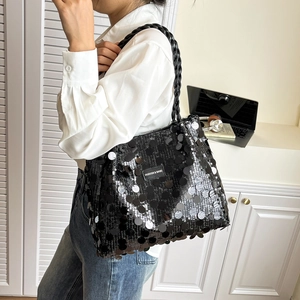 Fashionable black sequin tote bag with woven handles and metal logo tag shown on shoulder