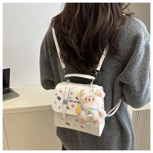 Détail du sac à dos en cuir blanc avec imprimés et charmant ours en peluche attaché