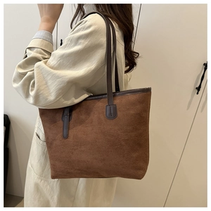 Détail du sac fourre-tout en daim marron montrant la texture mate et les anses renforcées
