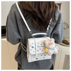 Détail du sac à dos blanc avec lettres colorées et charmant petit ours rose en peluche