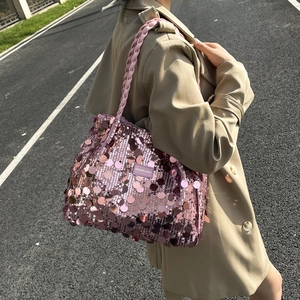Pink sequin tote bag with woven handles shown as a crossbody bag on a street style model