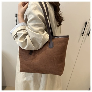 Sac fourre-tout en daim marron avec bandoulières en cuir foncé porté par un mannequin