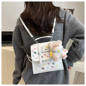 Détail d'un mini sac à dos en cuir PU blanc avec un petit ours en peluche rose décoratif