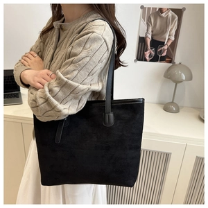 Détail du sac cabas en daim noir porté par un mannequin dans un intérieur chaleureux