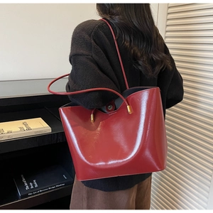 Detalle de bolso tote en charol rojo con herrajes dorados y cierre magnético