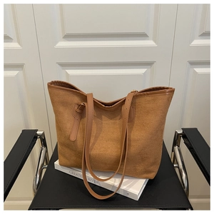 Grand sac cabas marron en toile avec bandoulière sur un livre, décor élégant