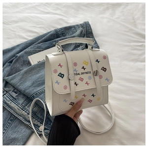 Détail d'un sac bandoulière blanc imprimé avec fermoir argenté sur un drap doux