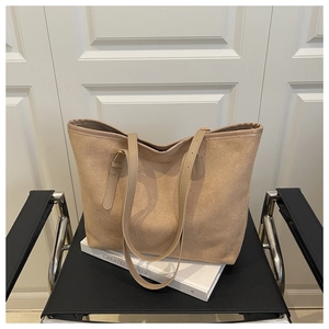 Détail d'un grand sac fourre-tout beige avec bandoulière en cuir sur une chaise vintage