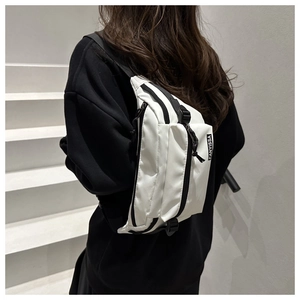 Detailed view of white nylon crossbody bag with black zippers and adjustable wide strap