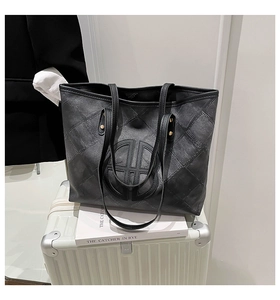 Detail of black washed denim tote bag with circular stitching on a white suitcase