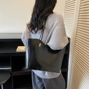 Fashionable black glossy tote bag with asymmetric wavy edge for casual autumn commute