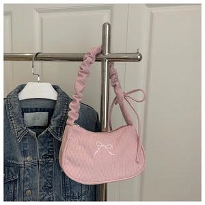 Detail of pink corduroy shoulder bag with embroidered bow and ruffled cloud strap