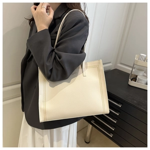 Close-up of ivory tote bag with lychee pattern leather and decorative stitching detail