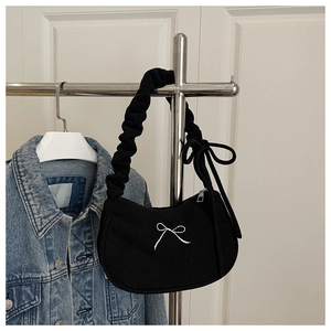 Detail of black pleated shoulder bag featuring silver bow embroidery and cloud strap