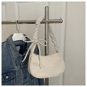 Detail of pleated handle and corduroy texture on cream shoulder bag with pink bows