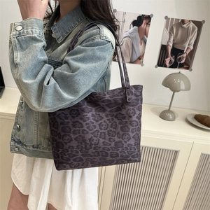 Stylish large leopard print tote bag in dark purple, worn with a casual denim jacket