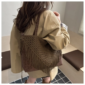 Detail of woven boho tote bag with long tassels and leopard print base shown on model