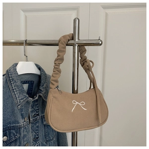 Detail of khaki corduroy shoulder bag featuring white bow embroidery and ruffled strap