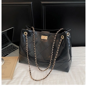 Dettaglio borsa shopper nera trapuntata con catene dorate e chiusura girevole in metallo