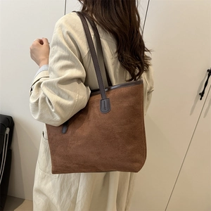 Sac fourre-tout en daim marron porté par un mannequin sur fond neutre chic