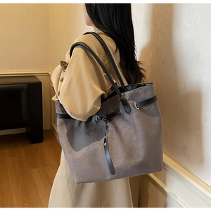 Détail du grand sac cabas en daim gris avec lanières en cuir noir et boucle en métal