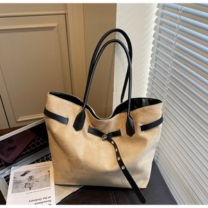 Détail du sac cabas en daim jaune sable avec bordures noires et boucles métalliques