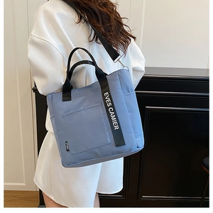 Detail showing the light blue oxford tote bag with a branded wide shoulder strap
