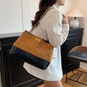 Borsa a tracolla bicolore trapuntata con catena dorata su modella in completo bianco