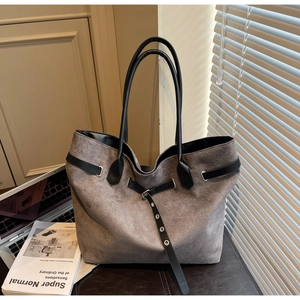 Détail du sac cabas en daim gris avec lanières en cuir noir et boucle métallique décor