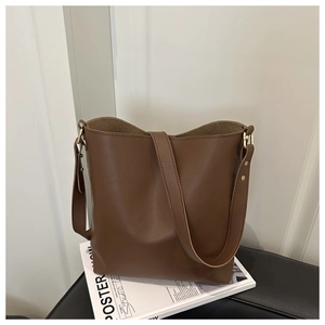 Detail of coffee brown leather bucket bag with gold hardware and wide shoulder strap
