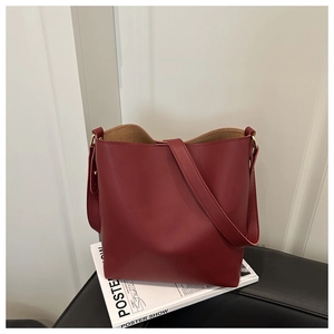 Detail of minimalist dark red bucket bag with matte leather and golden buckle