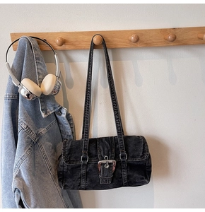 Gros plan d'un sac à bandoulière en denim anthracite avec boucle métallique sur crochet en bois