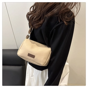 Détail d'un sac à bandoulière crème minimaliste avec étiquette en cuir marron
