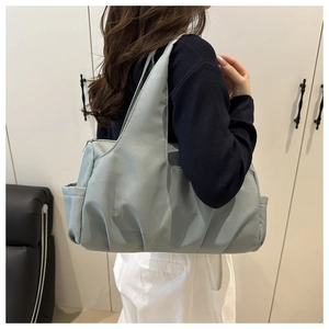 Dettaglio della borsa tote in nylon azzurro con tasca laterale e chiusura a zip robusta