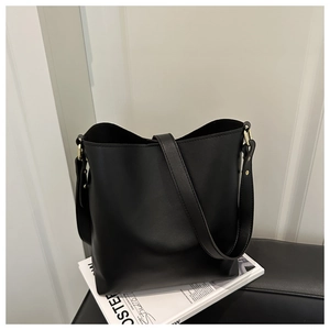 Close-up of minimalist black bucket bag featuring matte leather and golden ring hardware