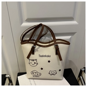 Detail of a beige tote bag featuring a cute black cat print and contrasting brown handles
