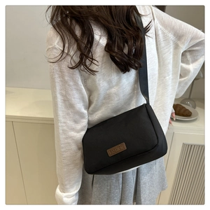 Détail d'un sac bandoulière noir tendance avec patch FASHION et large sangle ajustable